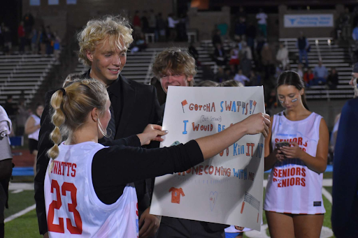 After the Powder Puff game, senior Cece Watts holds her homecoming proposal sign from senior Tyler Hayek’s surprise proposal. Hayek proposed after Watts scored two touchdowns, helping to secure the victory for the class of 2023. “It was shocking enough to see him in a suit, but when I turned around and found him holding the sign, I was ecstatic. It added to the thrill of the night as the cherry on top,” Watts said. 
