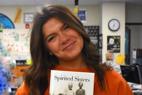 Sophomore Sadie Burgess poses with her grandmothers novel Spirited Sisters. Burgess grandmother grew up in India and has written 20 novels with her experience.