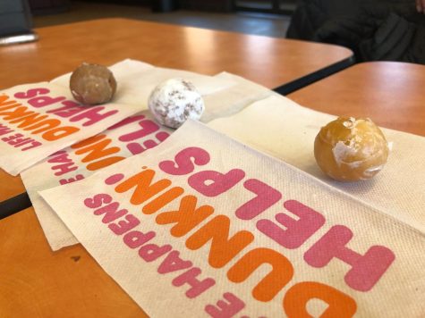 Three munchkins reviewed in the article sit on a table on top of Dunkin Donuts napkins.