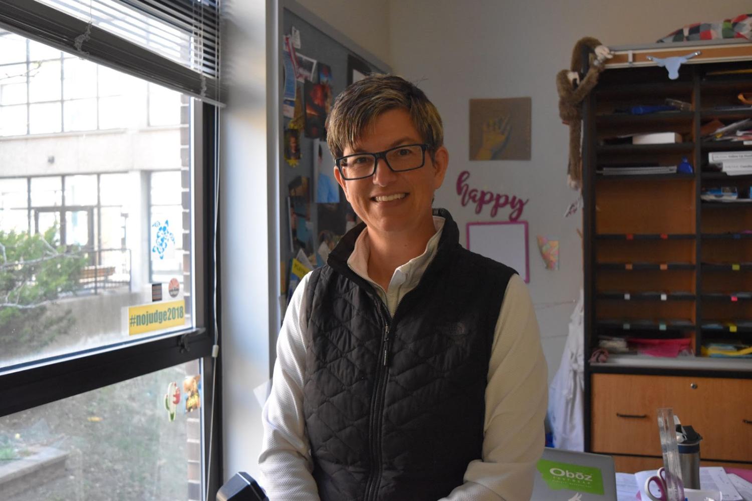 Science teacher Amy Van Matre-Woodward stands in her classroom and smiles at the camera.