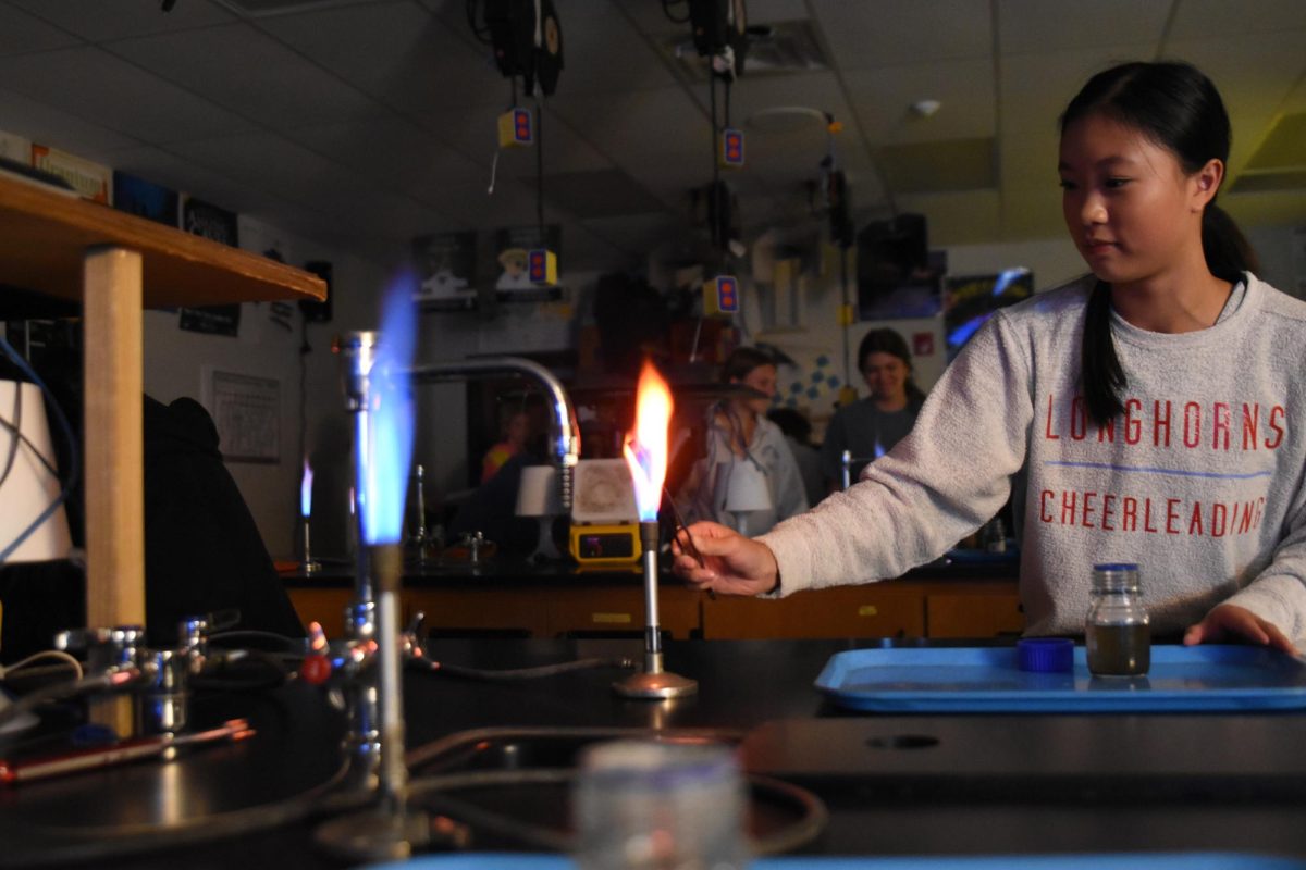 Kickstarting+a+flame%2C+sophomore+Allison+Rueschoff+begins+her+lab+experiment+by+inserting+an+element+into+a+liquid+in+her+Honors+Chemistry+class.+Student+scientists+explained+how+elements+can+release+photons+within+this+experiment.+%E2%80%9CI+liked+getting+out+of+worksheets+and+labs.+This+is+one+of+the+best+experiments+we+do+in+this+class%2C%E2%80%9D+Rueschoff+said.