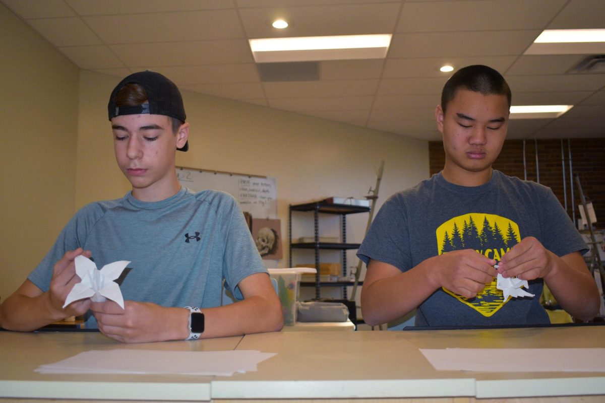 Freshmen Cole Barton and Preston Priest make origami flowers during free time in their Drawing 1 class. Both gained an affinity for origami through the internet and further practiced this art under the guidance of West High Drawing 1 teacher Kat Briggs. “Their origami pieces are especially intricate. Both use multiple small pieces of paper that fold and interlock, enabling their sculptures to move and also simulate textures. They also use very precise folds, and I appreciate the careful craftsmanship that [goes] into their art,” Briggs said.