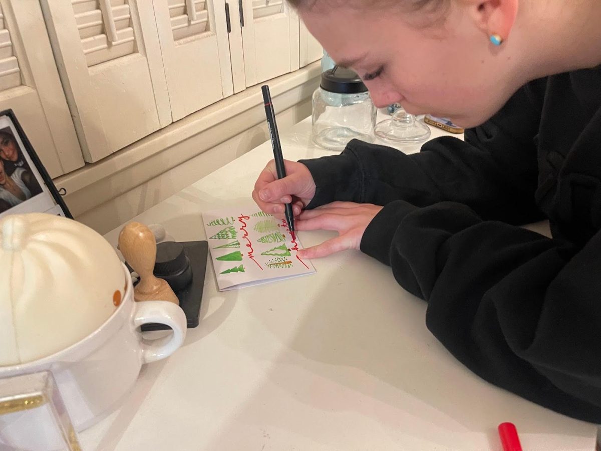Lettering+%E2%80%9CMerry+Christmas%2C%E2%80%9D+sophomore+Roxie+Schopp+sits+at+her+desk+creating+a+new+holiday+card+for+her+greeting+card+business.+She+started+her+business+her+freshman+year+as+a+way+to+express+and+do+something+with+her+love+for+calligraphy+and+art.+%E2%80%9CI+started+%5Bmy+business%5D+because+I%E2%80%99ve+always+been+an+economic+person.+It+felt+right+to+do%2C+and+I+knew+I+could+continue+it+and+do+it+well%2C%E2%80%9D+Schopp+said.+