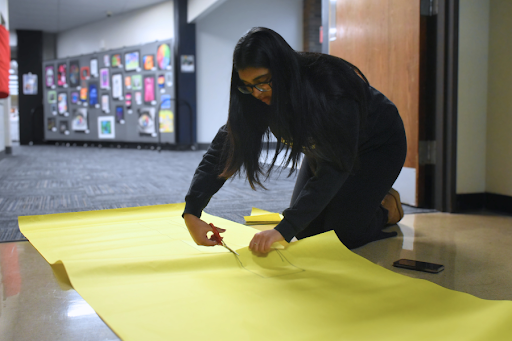 Cutting out a square for the door handle, senior Vita Madamanchi prepares a sheet of paper to be decorated by National English Honors Society. The door decoration was inspired by the contemporary poet Jericho Brown, whose work has been honored with several awards, including the 2020 Pulitzer Prize. “Not only was it fun being able to read a new enlightening poem and be creative, but I was also able to contribute to celebrating the work of a poet, promoting diversity, inclusion and cultural appreciation. Literature from marginalized communities provides representation for people who have historically been underrepresented or misrepresented in mainstream media and literature. Seeing themselves reflected in literature can empower individuals from these communities and validate their experiences,” Madamanchi said. 