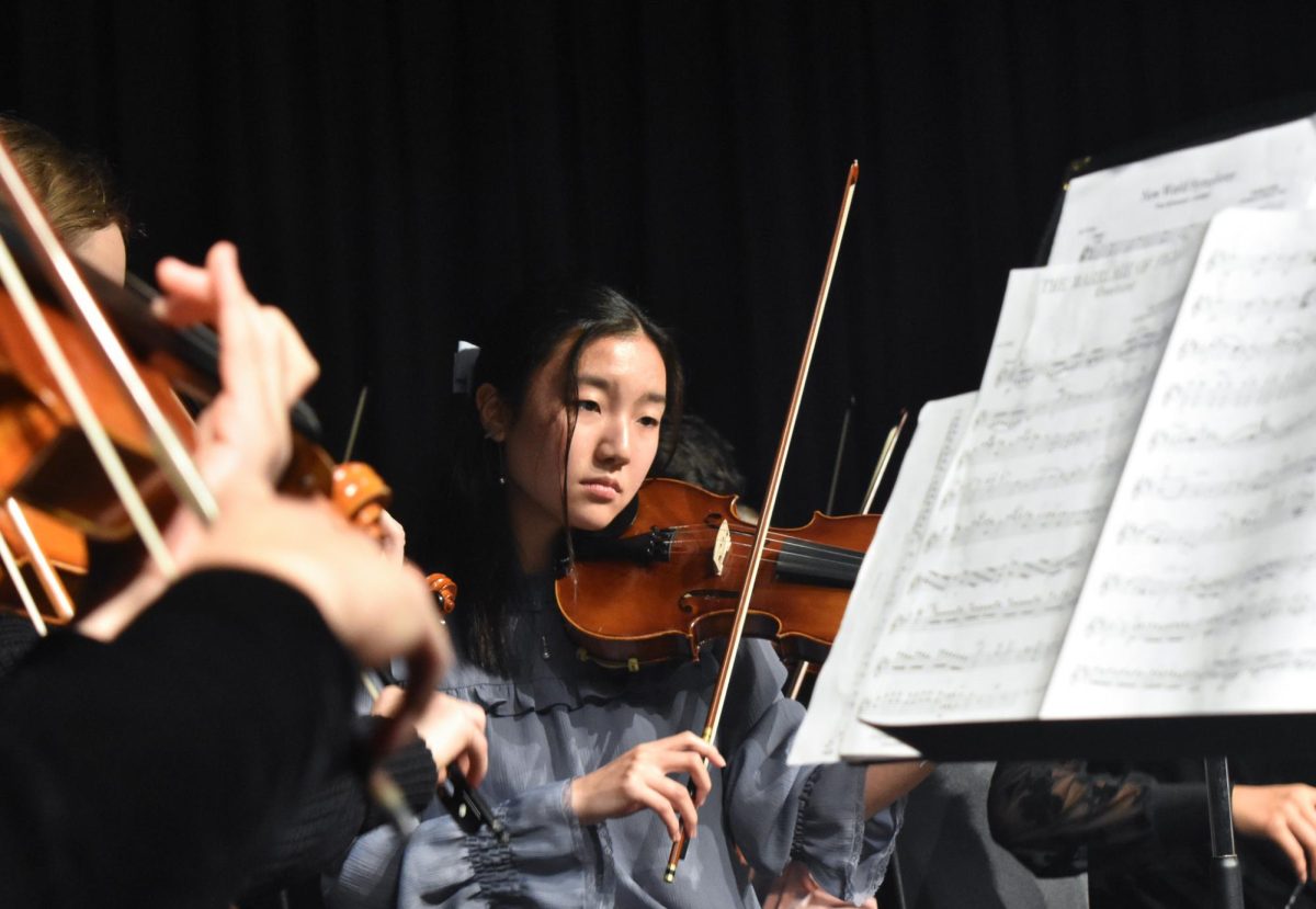 Drawing the bow across her violin, senior Yena Ahn plays New World Symphony at the orchestra concert on April 30. The symphonic orchestra combined with the band for the last performance of the school year. “This was our seniors last concert, so we were able to wear a different attire than the usual black to stand out,” Ahn said. “Its definitely bittersweet because Ive done orchestra for four years and most of the people in symphonic [orchestra] are seniors.”