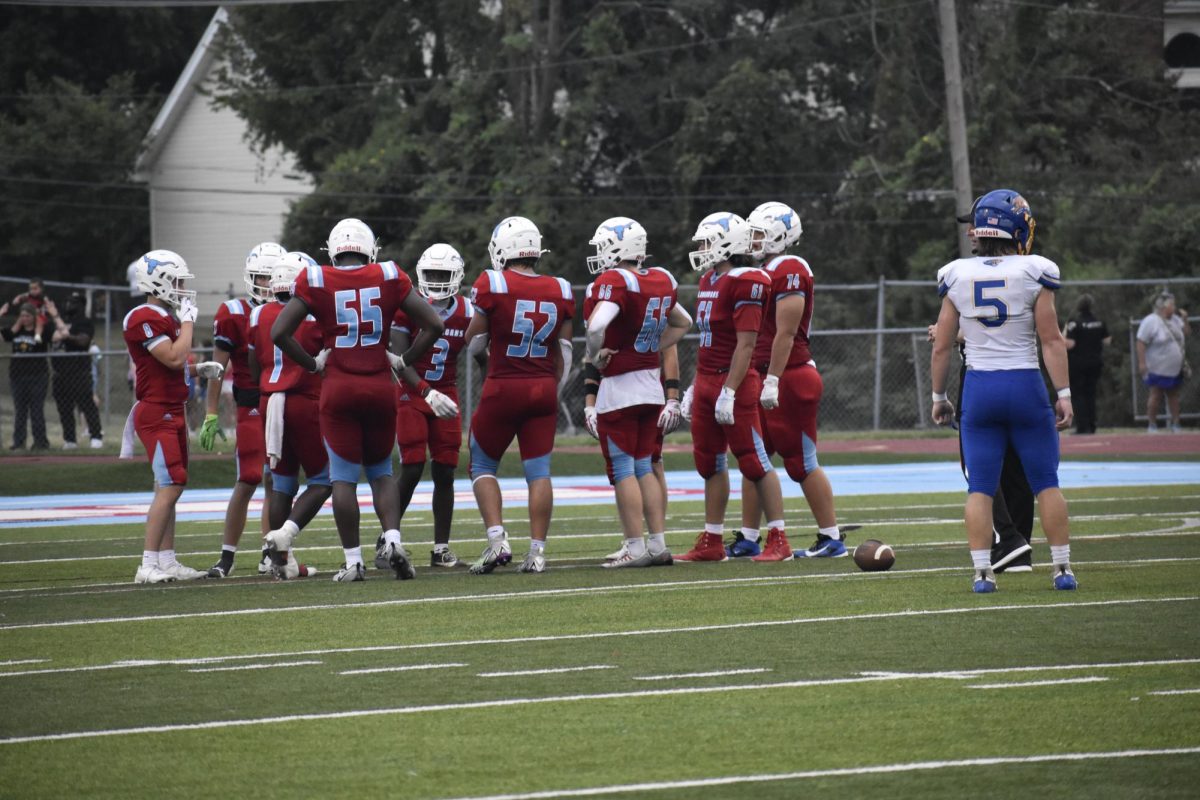 Huddled with teammates, sophomore Nic Hayek listens intently to upperclassmen. Hayek started in the game against Seckman on Aug.30.  “[The upperclassman] welcomed us and helped us adjust. [They] helped us get used to the speed of varsity football,” Hayek said. (Nikhita Cherukuri)
