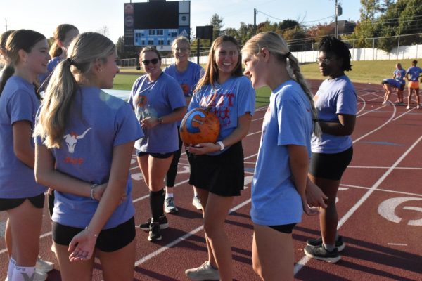 Standing with girls cross country team mascot Pump the pumpkin, senior Sydney Etchason laughs with her teammates. Before the team’s senior night, Etchason undertook an odyssey to recover the pumpkin, which had been stolen by boys cross country. “We went through practice, and then a little birdie told me that it was in [senior] Emmett [Vernon's] car. I [offered Vernon] $50 to give us our pumpkin back, and we got Pump back,” Etchason said.