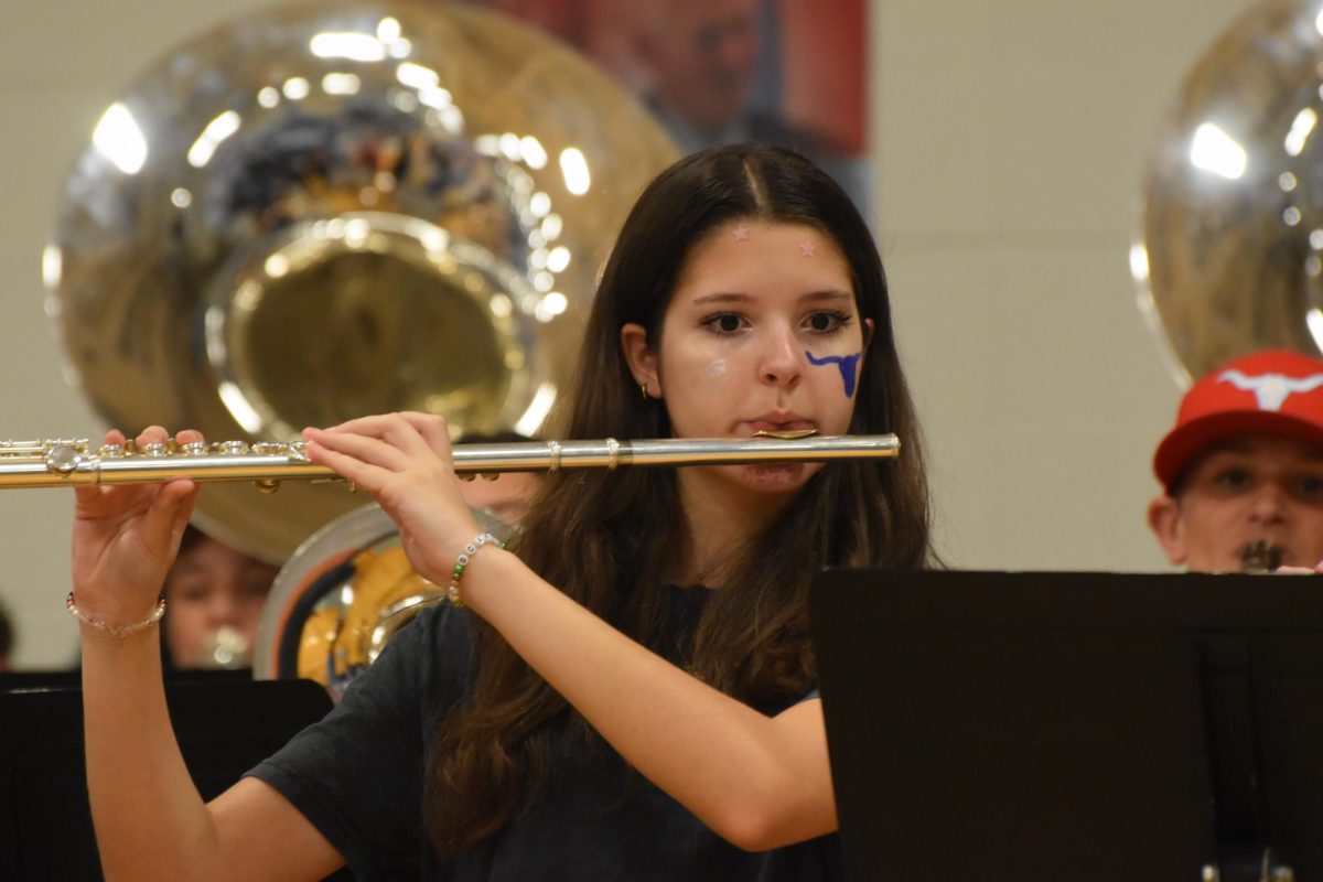 Experiencing her first pep rally from a performer’s lens, freshman Ella Melter plays the flute as students enter the gym. A band member since middle school, Melter prepared for over three years in anticipation of the high school marching band events. “All the people getting excited was the [best part. The] atmosphere was very climactic and energetic,” Melter said.
