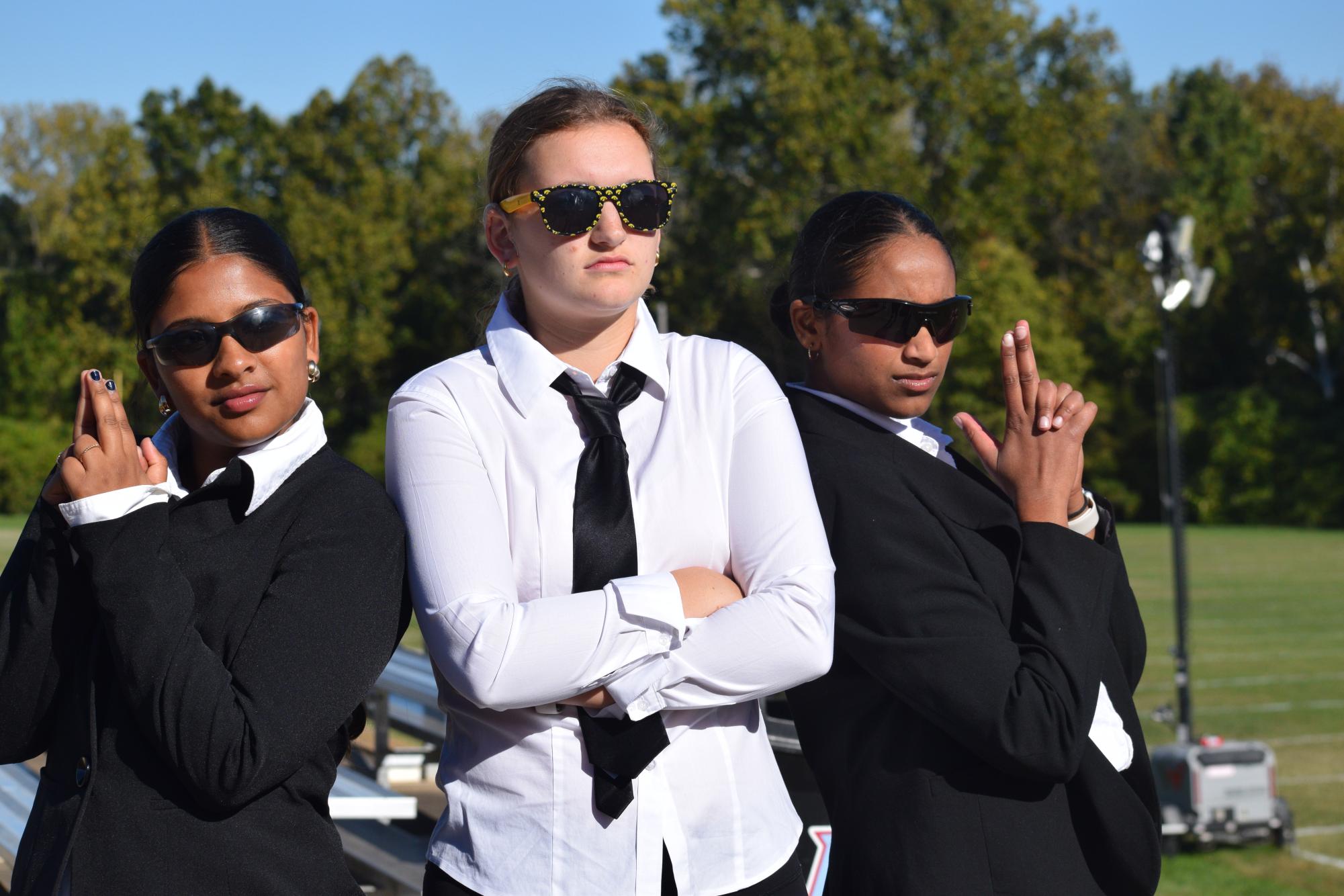 Dressed in crisp suits, senior Brooke Hoenecke (middle) poses with seniors Shirah Ramaji (right) and Risa Cidoni (left). The trio chose to dress up as Men in Black for the Halloween practice. “[My favorite part was] getting to spend time with some of the [junior varsity] members. We don’t get to hang out with them and socialize as much because we practice with varsity only,” Hoenecke said.