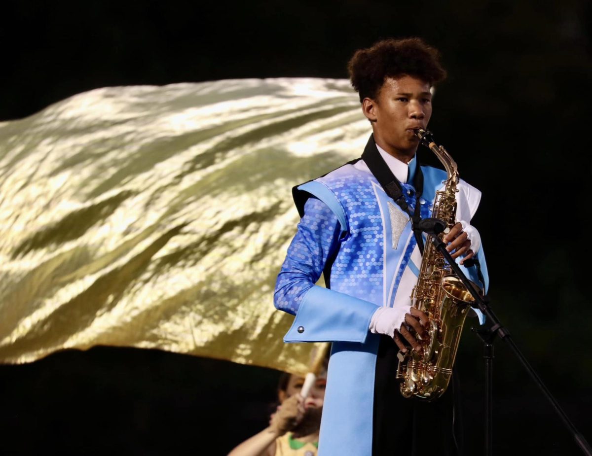 Junior TJ Polack plays his saxophone solo at halftime for the 2024 marching band show, ‘Coloring Book.’ This year, Polack was one of two soloists in the marching band. “[Polack] is very hard on himself. [His saxophone solo] sounds amazing [and] everyone [cheers] for him; [still], somehow, he thinks it’s a bad performance and he's down. What he does is not easy. It takes a lot of confidence as a person [and] a lot of musical skill to be expressive, and he's doing an amazing job,” drum major and senior Dominic Perez said. (Courtesy of Christina Block)