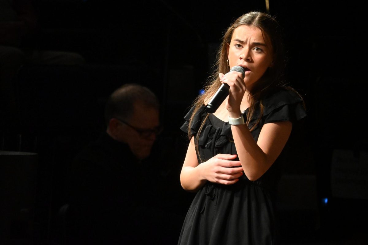 Standing up tall, senior Mackenzie Silva sings “Big Yellow Taxi” among the Jazz Choir. Silva has been a member of the Jazz Choir for two years. The Jazz Choir worked hard leading up to the show.  “[My favorite part of the concert was] our rehearsal an hour before anybody else was there because we're all singing together, and we all feel nervous, but it's a fun nervous energy,” Silva said. 