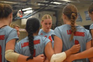 Surrounded by teammates, junior Katie Byergo is coached by Susan Anderson during a team huddle between sets. Anderson told the team that their energy was lacking, and the team needed to start getting excited about every point. "Cheering on my teammates is something I love to do. Celebrating their success over mine- it's my team over myself," Byergo said.