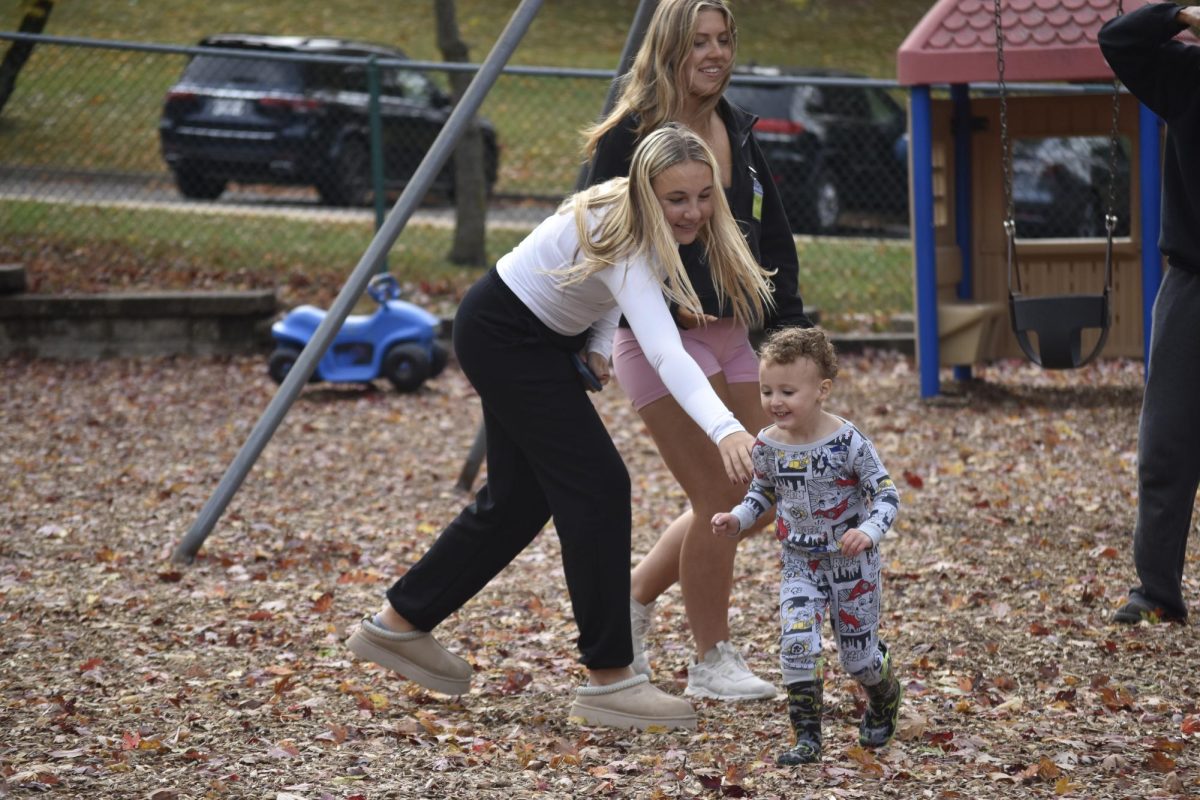 Reaching out her arm, freshman Madelyn Mills engages in a game of tag with a young student during her visit on Oct. 31. The high schoolers not only interacted with the preschoolers inside the classroom but also sometimes outside depending on the schedule. “I took [Child Development] because I thought that [it would bring] opportunities for my future [by allowing] me to get a further viewpoint on the care that a child needs,” Mills said. 
