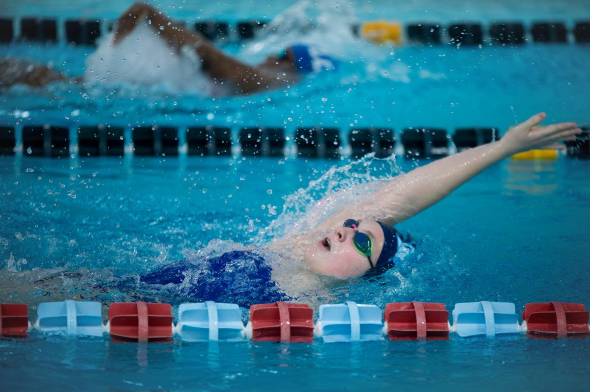 Reaching for the wall, sophomore Bella Lamb glides through the water in the 100-meter backstroke on Jan. 28 against Lutheran South High School. Lamb’s main event has been the 500-meter freestyle and she worked the most on pacing during practice. “I really wanted to go to state for my 500[-meter freestyle] and the state cut is six minutes. At the Kirkwood Invite, I went 5:47, so I currently have a state cut in the 500. And so [now] I'm working towards getting a lower time,” Lamb said.