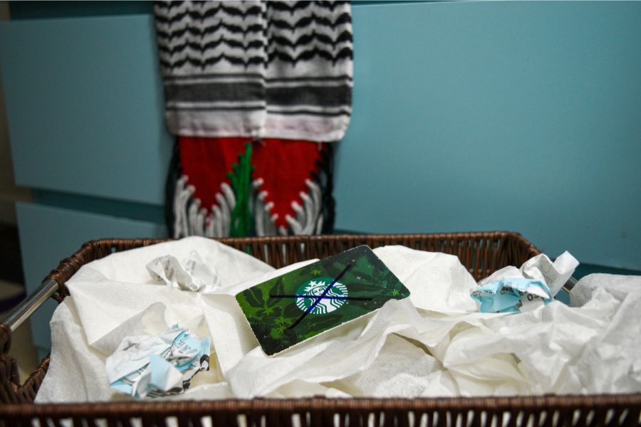 A discarded Starbucks gift card sits among crumpled tissues and trash in front of a Palestinian scarf, symbolizing the ongoing boycott against the company. The controversial ongoing war between Israel and Hamas saw support from various corporations, including Starbucks, which faced backlash after involving itself in a tweet by Starbucks Workers United expressing solidarity with Palestine. “If you continuously buy Starbucks knowing they don't align with your moral values, then you are going to be dehumanized to that. The point of the boycott is showing Starbucks that these groups of people are not with them,” junior Zoya Hasan said.