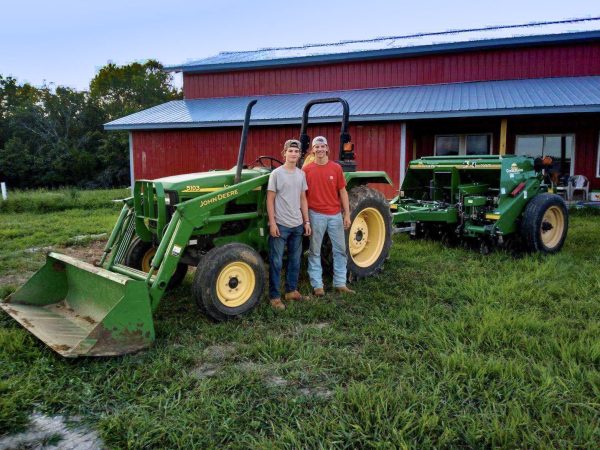 Senior Adam Zerega stands with senior Dexter Brooks by farm equipment. Zerega often worked with friends and family on his farm. “I've been able to go to my family's farm since I was born. I [spend] at least three weekends a month [on the farm], so I'm there all the time,” Zerega said.