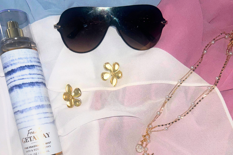 Sunglasses, Bath & Body Works body spray, floral earrings and a seashell necklace set sit on top of three chiffon head scarves, ready to complete a look. 