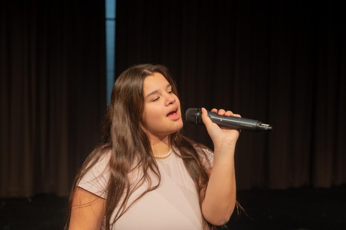 Gazing across the stage, sophomore Alexis Monteleone performs in the school theater.  The Monteleone family’s band “Monte and the Machine” has been releasing music since 2012, but Alexis started her own solo career in 2024 with the release of her first single, Crying Skies. “My whole family is very musical, [and I especially] love writing [songs with them],” Monteleone said.