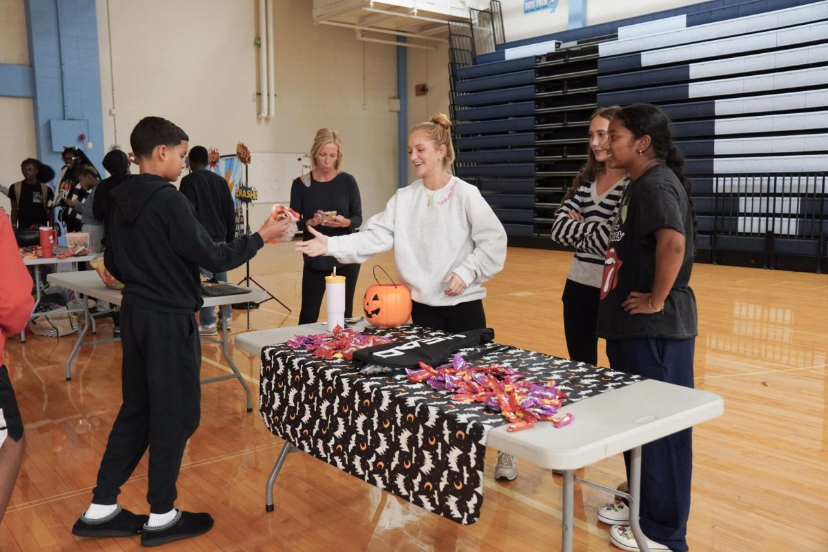 Dressed up as the varsity girls’ tennis coach Katelyn Arenos, senior Kate Johnson and junior Mireya David hand out candy at West High’s annual trunk or treat event. This year, the trunk or treat was moved inside as a result of adverse weather. “As a senior, I care less about Halloween now. Teachers will bring their kids and families [to West’s Trunk or Treat], but there were fewer [this year] because they just thought it was canceled [due to the] rain. [With] Halloween, I think you care less the older you get,” Johnson said.