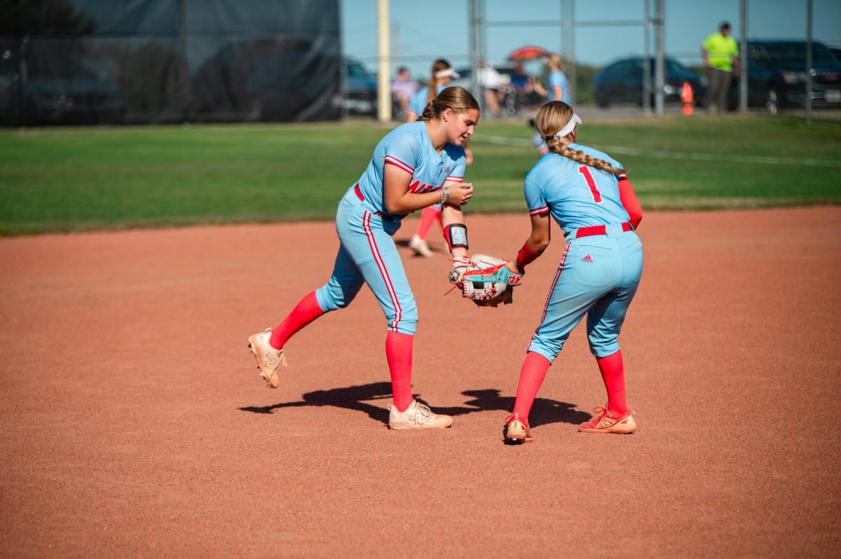 
Junior Noor Hacking hands the ball off to sophomore Natalie House during a game against the Oakville Tigers on Sept. 8. Hacking played third base, and her main objective was to get people out and hit the ball deep. “I love playing third base because it is not only really fun, but it is also a big part of the team’s defense,” Hacking said.