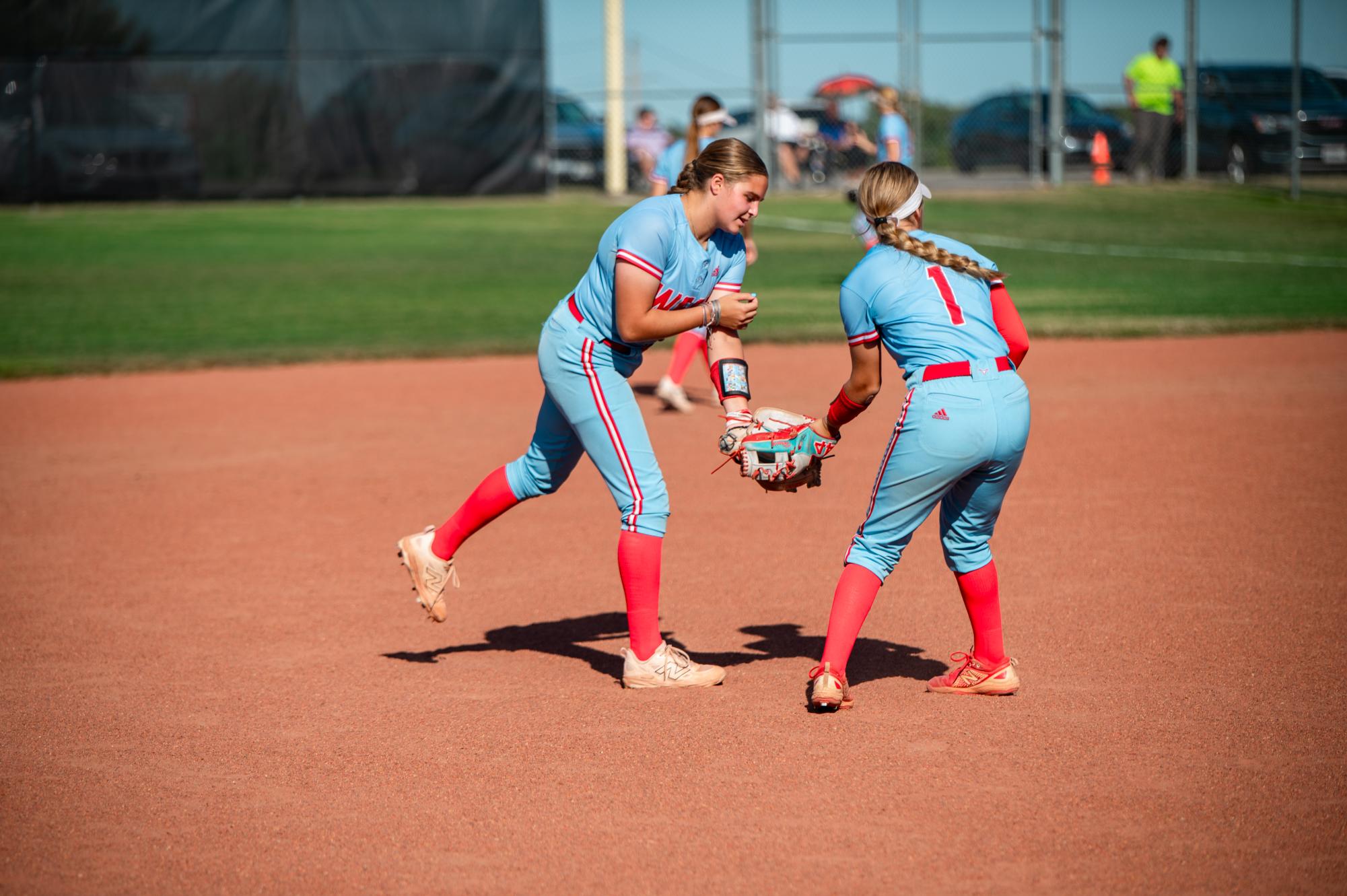 
Junior Noor Hacking hands the ball off to sophomore Natalie House during a game against the Oakville Tigers on Sept. 8. Hacking played third base, and her main objective was to get people out and hit the ball deep. “I love playing third base because it is not only really fun, but it is also a big part of the team’s defense,” Hacking said.