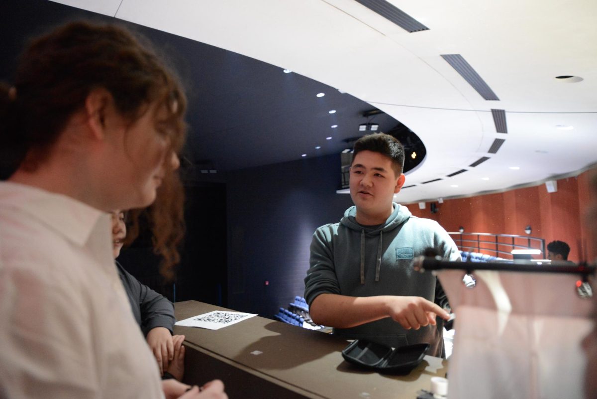 Speaking to junior Kit Bowers, sophomore Max Chung assists cast members with their microphones before a dress rehearsal of “Lost Girl.” Chung joined West Middle School’s technical crew in sixth grade and now serves as the sound department lead at West High. “Sound is a vital part of the actual performance, because without [proper microphones], it’s hard for the actors to project enough,” Chung said.