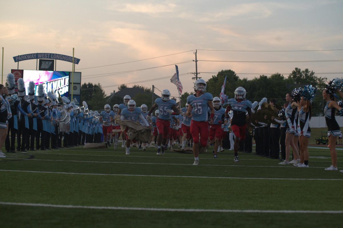 Senior Easton Kimbrough rips through a sign to help lead his team on the field for the Homecoming football game on Sept. 12. The Longhorns played McCluer North High School. “We do a chant every time before we run through the poster,” Kimbrough said. “It gets us hyped up and ready for the game, especially when we get to run out in front of the crowd.”