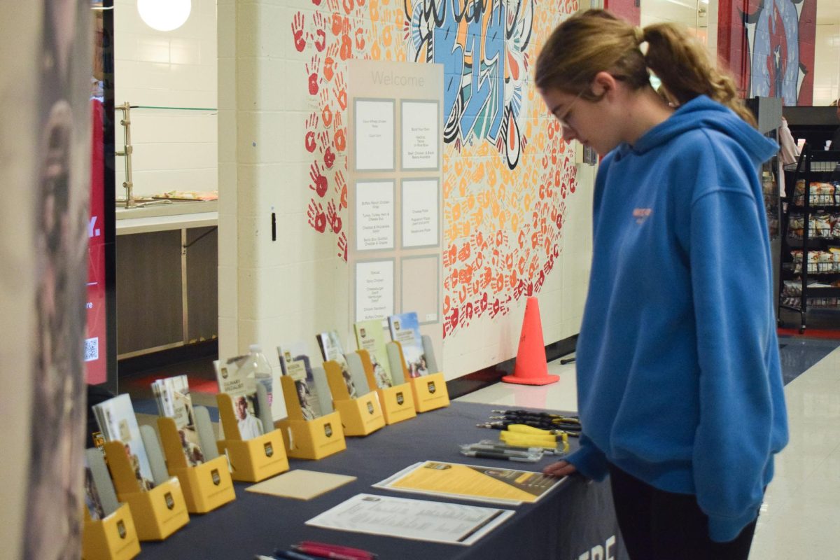 Freshman Daphne Stokes looks at a table with Veterans Day flyers and information on Nov. 11. Stokes, along with other West High students, like senior Alexander Lewinski, passed by the table in the cafeteria with army recruitment information and giveaways for students to observe during lunch. “Talking with [the recruiters] has definitely helped me [find] where I wanted to go, more than anything else,” Lewinski said.