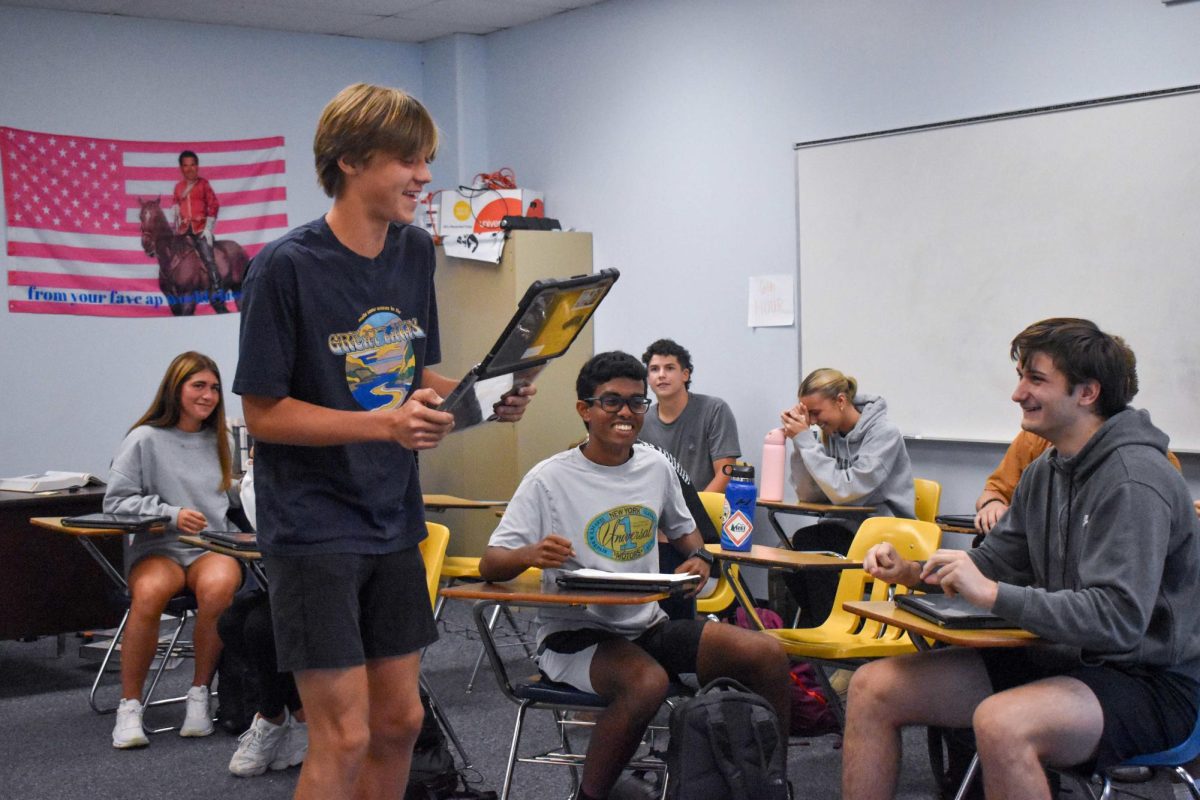 Junior Tom Peters laughs as he stands in front of the class during a bachelorette-themed project in the History IPBL class, while classmates join in on the laughter and judge his performance. “It's fun to watch students work on projects like this, it lets (them) experience history they get taught and really get into it,” social studies teacher Jim Hermann said.