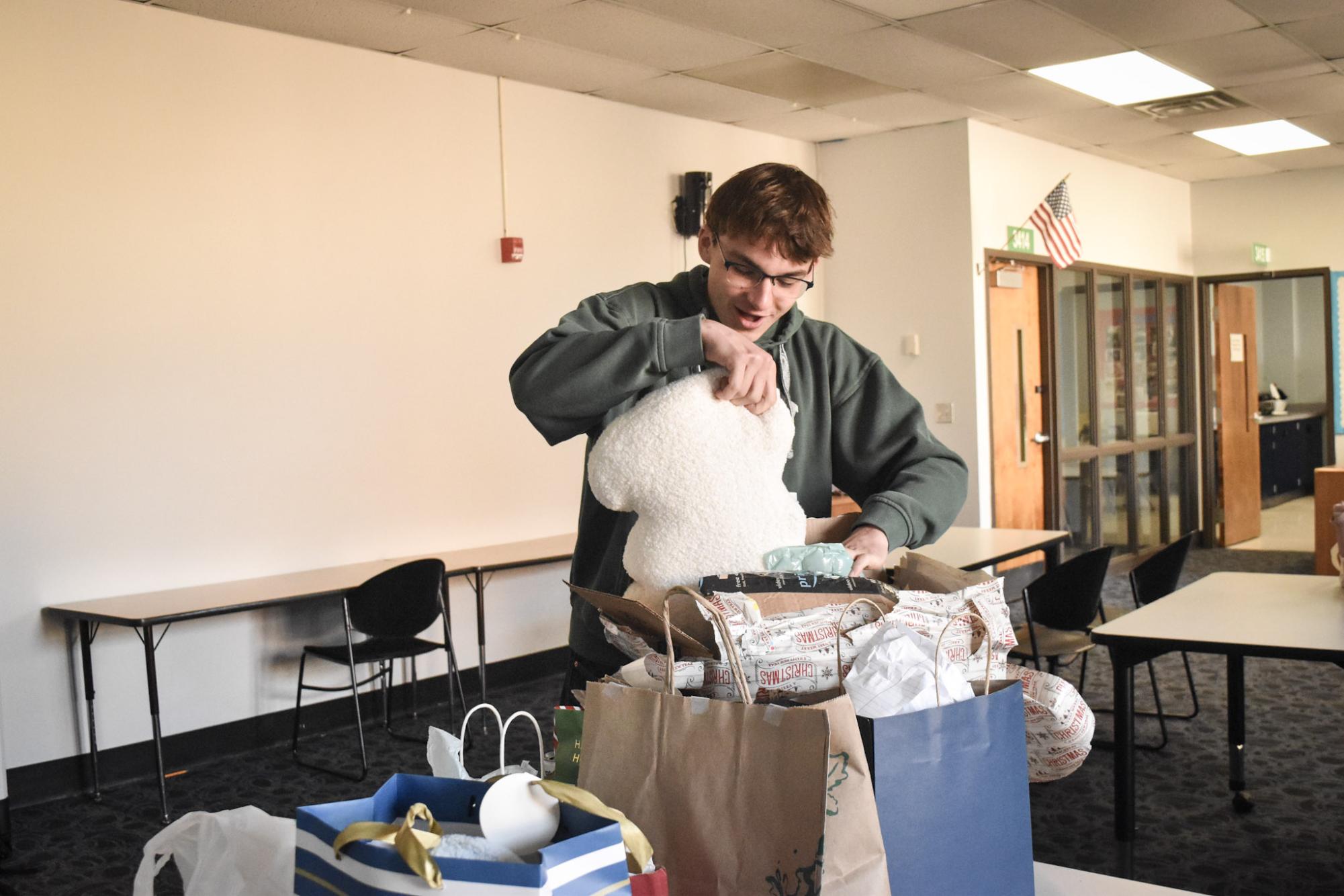 Unwrapping and pulling out a stuffed animal from a box, sophomore and ABC Club executive member Dylan Smith opens his gift for the White Elephant gift exchange hosted by ABC on Nov. 8. Smith helped plan for the event with other executive members including co-president and junior Bethany Liao. “We wanted to host a special holiday event. I think people definitely had fun, especially when the stealing component of white elephant came in, because then people could bargain with each other for gifts,” Liao said.