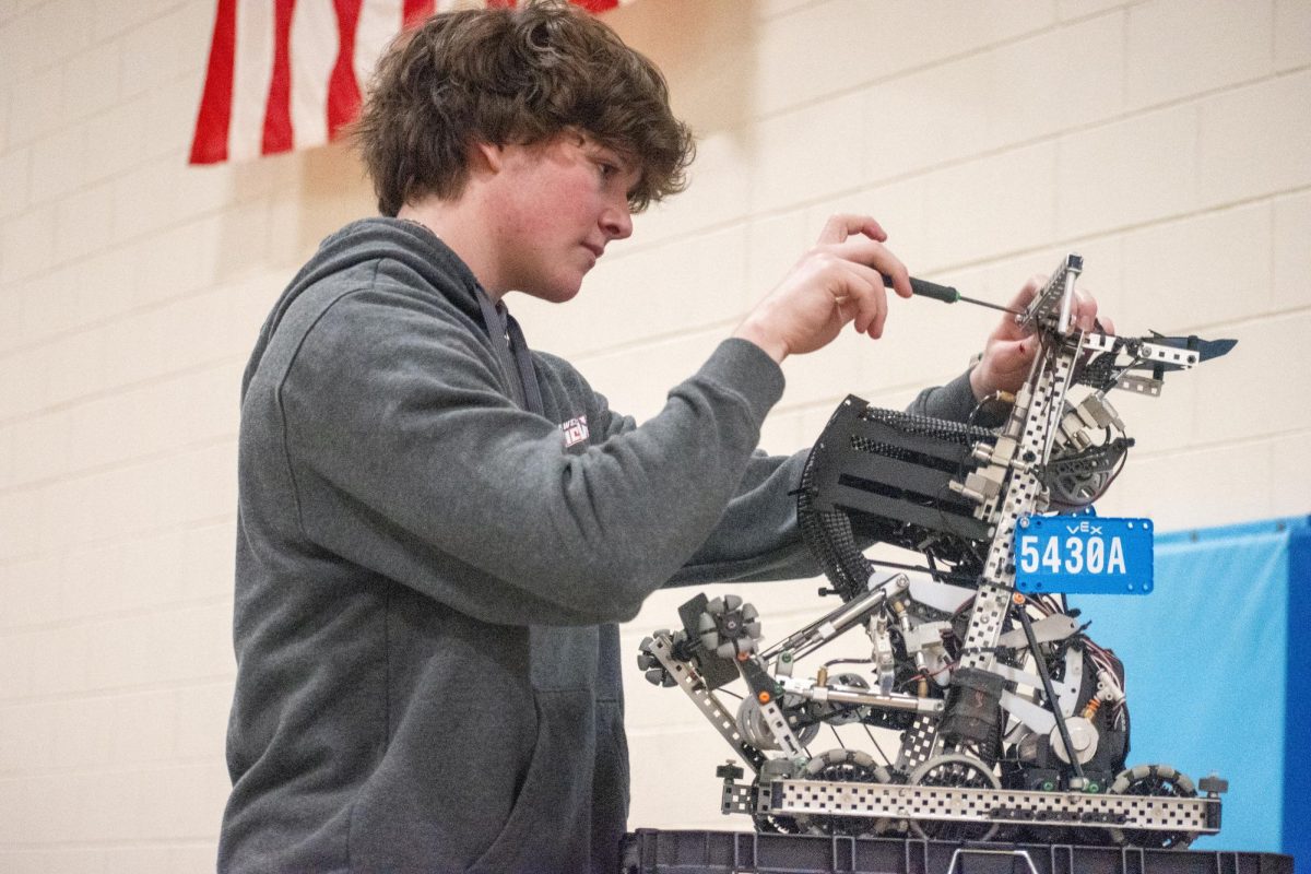 Screwing in a nail, junior Adam Thomas repairs team Blue Brain’s robot. After working their way up to semifinals, the team’s robot broke in the middle of the match, crushing their chances of championing the competition. “I care more about our overall engineering than winning, [which] balanced out our struggles during the qualification rounds,” Thomas said.
