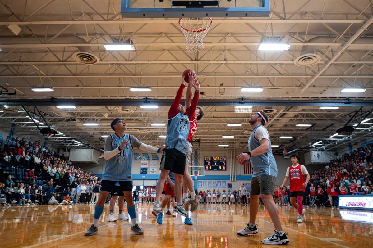 Reaching for a rebound, Principal John McCabe tries to lead the teachers to a comeback during the annual teachers vs. students basketball game Dec. 15. This year, in an effort to involve more students, the game was held during the winter pep rally. “[Parkway West] is a special place, with special kids and special teachers. Any time we all get together, it feels like everybody is connected. This school is great, and [although] I know that, not everybody does, and it’s a great feeling to be able to put that on display,” McCabe said. 

