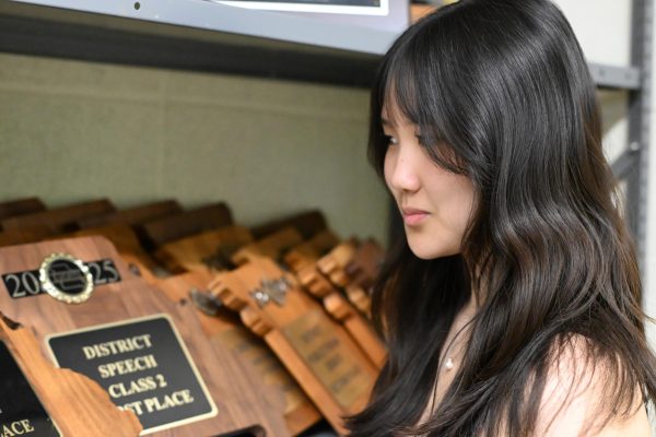 Reflecting on previous years, junior Bethany Liao looks at plaques in the Speech and Debate room. With her partner, senior Yein Ahn, Liao earned first place in Public Forum debate at the MSHAA Speech and Debate District Tournament on March 6 and 7. “I really want us to do good, and, even if we don't, I want it to be a memorable experience for [Ahn] because this is our last debate together,” Liao said.
