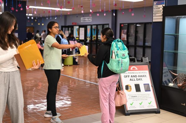 Junior Bethany Liao and sophomore Srinidhi Sripada pass out poems at the front entrance on April 29. Sripada volunteered for the event as a member of the National English Honor Society.  “I'm surprised by the [number] of people who were always excited about getting a poem,” Sripada said.